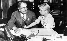 Jackie Cooper signs his MGM contract in the presence of studio head Louis B. Mayer in 1931.
