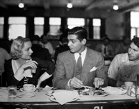 Carole Lombard and Clark Gable sitting at the lunch counter with the rest of studio's employees
