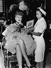 Helped by her maid Frizella Robinson, Claire Trevor refreshes her makeup on the set of Honky Tonk (1941)
